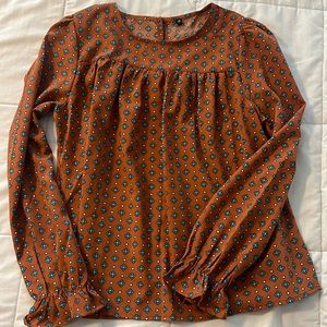 Long sleeved, silk top with a ruffled sleeve detail.